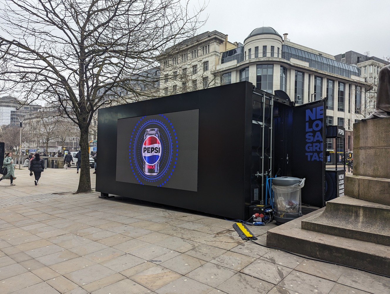 Pepsi branded shipping container conversion activation for product sampling campaign on busy high street handing out free cans of pop to passersby in Manchester