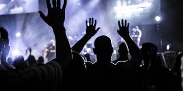 Festival-goers with hands in air at outdoor event 