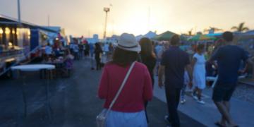 crowd walking past pop-up event structures at outdoor festival 