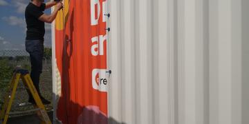 Branding and vinyl wrapping graphics onto corragated shipping container conversion for upcoming event tour