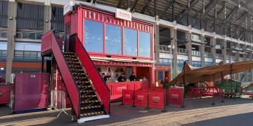 shipping container bar hire at rugby stadium with large crowd and branded setup